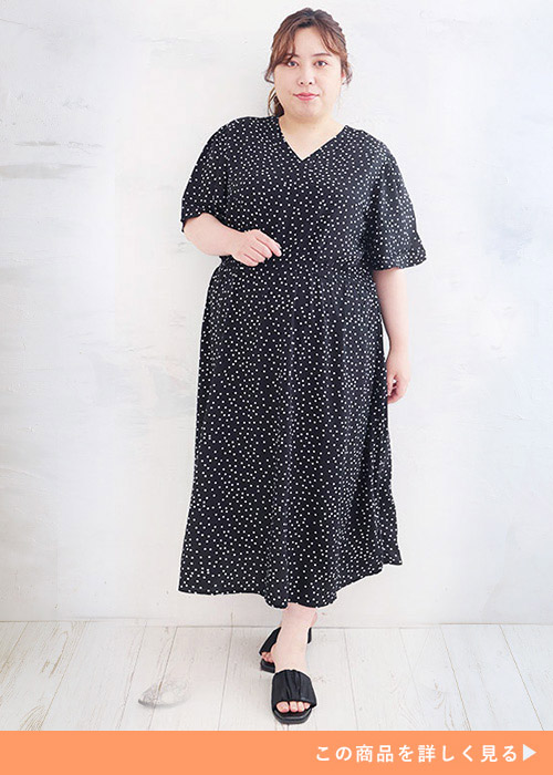 ドット柄のVネックワンピースに黒いサンダルを履く女性