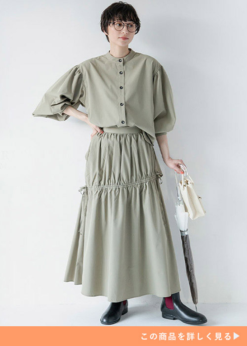 カーキのボリュームシャツとギャザー付きスカートのコーデにレインブーツを履く女性