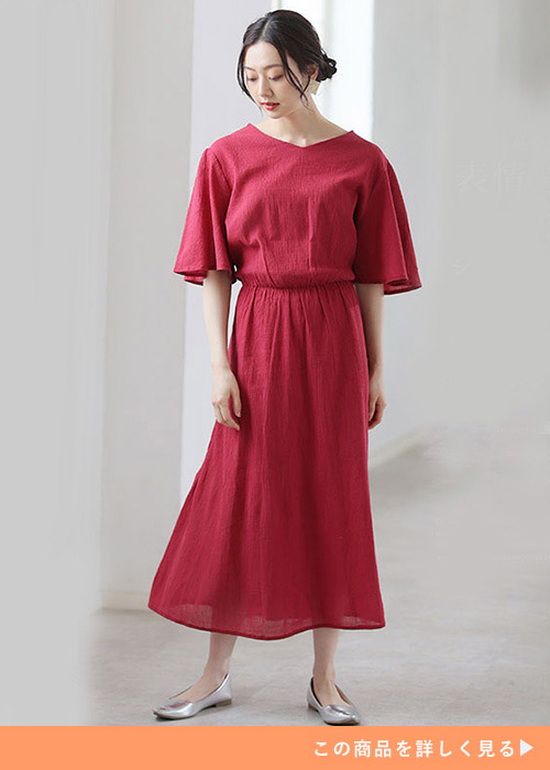 レッドのコットンワンピースにシルバーのフラットシューズを履く女性