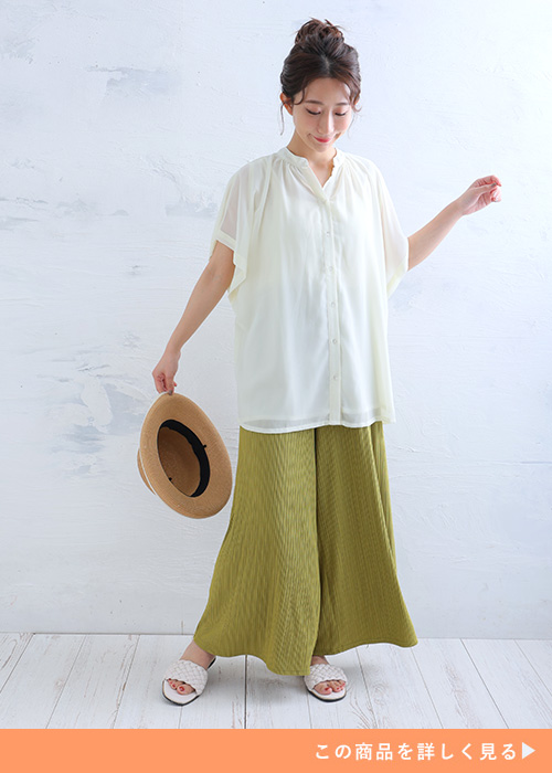 透け感のあるホワイトシャツとイエローのパンツのコーデにサンダルを履く女性