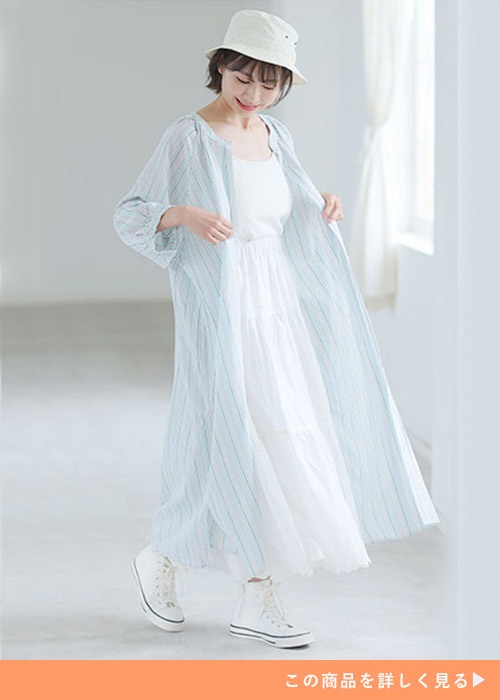 ホワイトワンピースにロングワンピースをレイヤードして白いスニーカーを履く女性