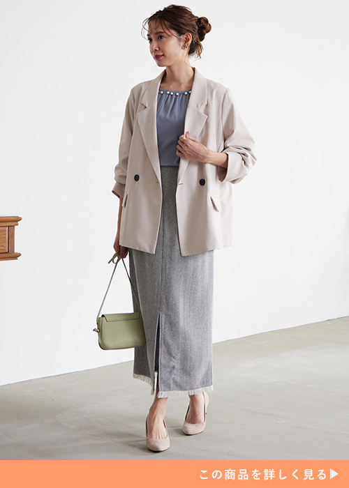 アイボリーのテーラードジャケットとパール付きブラウスとロングスカートのコーデの女性