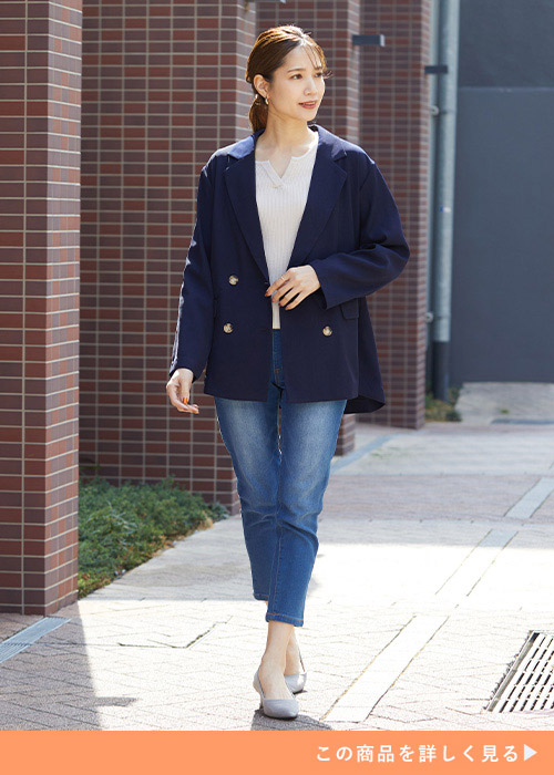 ネイビーのジャケットと白のシンプルトップスとデニムパンツのコーデの女性