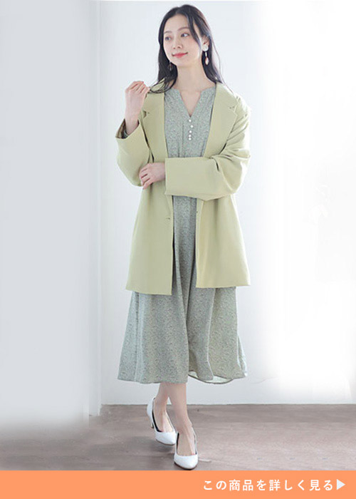 ライムイエローのテーラードジャケットとシフォンワンピースのコーデに白いパンプスを履く女性