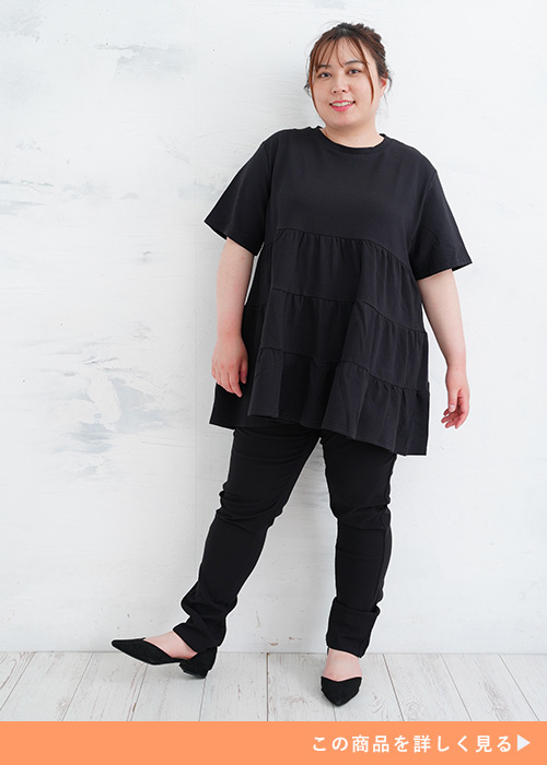 ブラックのティアードトップスを着て、黒のレギンスパンツを履く女性。