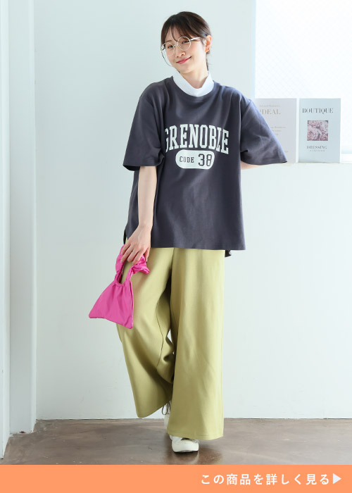 黒のロゴTシャツを着てワイドパンツを穿く女性