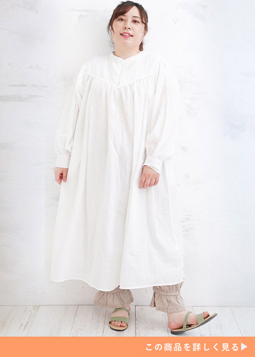 白のワンピースを着て、下にベージュのパンツを履く女性