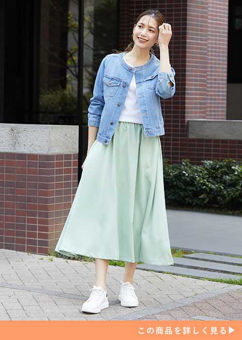 白T×ミントグリーンのフレアスカートに、デニムジャケットを羽織る女性