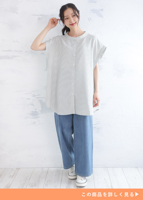 デニムパンツに白と緑のストライプ柄ビッグシャツを着る女性