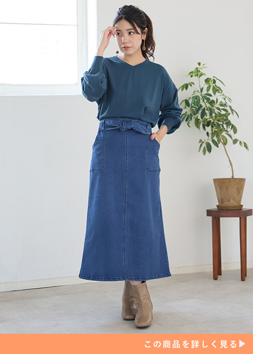 デニムのナロースカートとＶネックトップスのコーデにベージュのブーツを履く女性