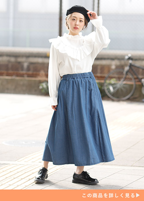 デニムのフレアースカートとブラウスのコーデに黒スニーカーを履く女性