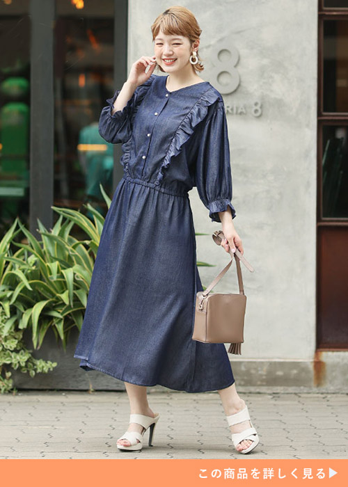 デニムフリルワンピースにベージュのバッグを合わせて、ホワイトのサンダルを履く女性