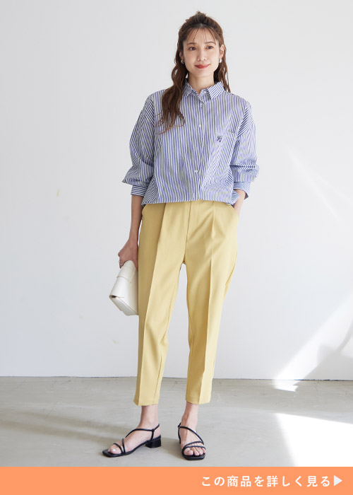 ストライプ柄のシャツを着て、イエローのテーパードパンツを履く女性