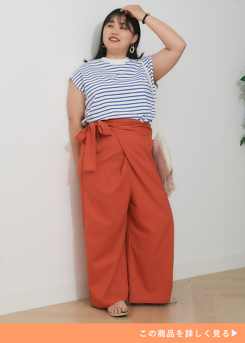 白×青のボーター柄フレンチスリーブトップスを着て、オレンジ色のラップパンツを履く女性