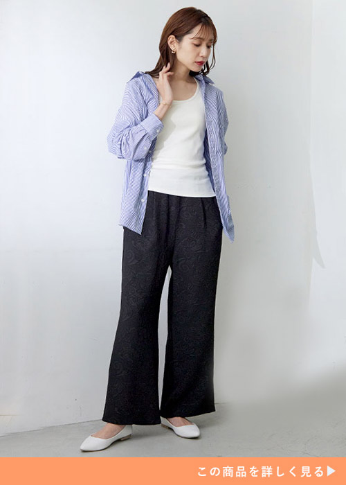 白のタンクトップ×黒のジャカード生地パンツに、ストライプ柄シャツを羽織る女性