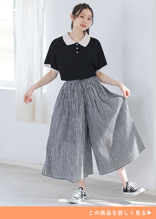 ポロシャツ風デザインのトップスを着て、ギンガムチェック柄のガウチョパンツを履く女性