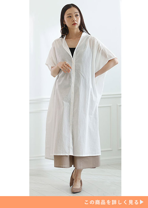 白のシャツワンピースの下に、黒のタンクトップ×ベージュのガウチョパンツを着る女性