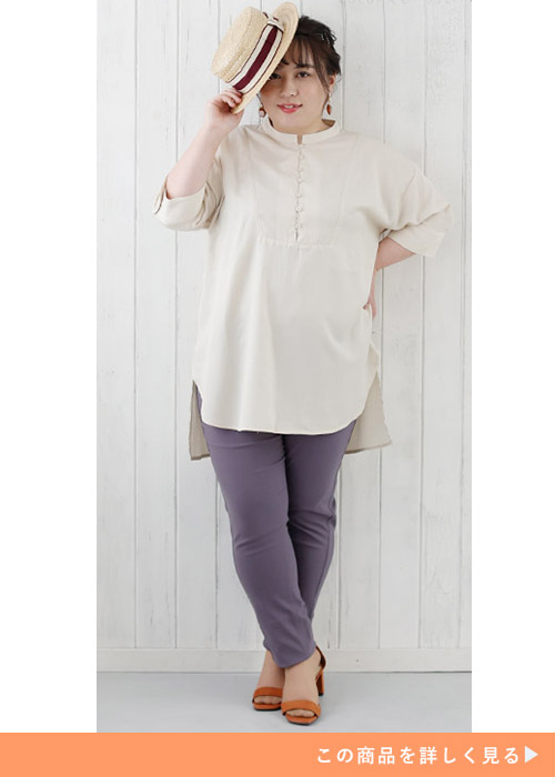 アイボリーのスタンドカラートップスを着て、くすみ紫のスキニーパンツを履く女性