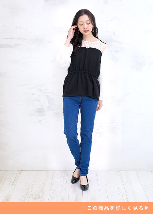 白のレースブラウス×黒のビスチェを着て、スキニーデニムを履く女性