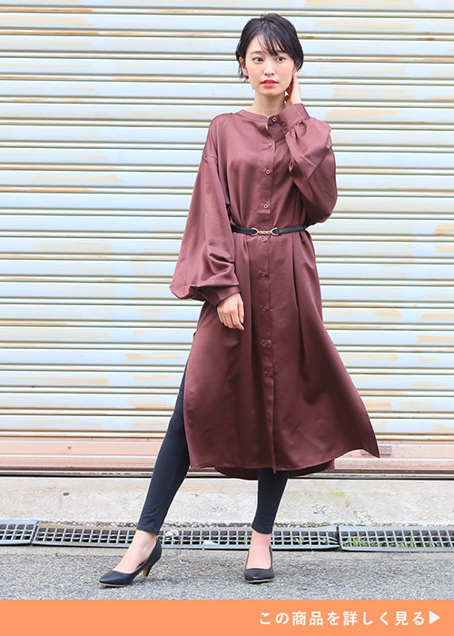 モカ色のサテンワンピースを着て、黒のスキニーパンツを履く女性。