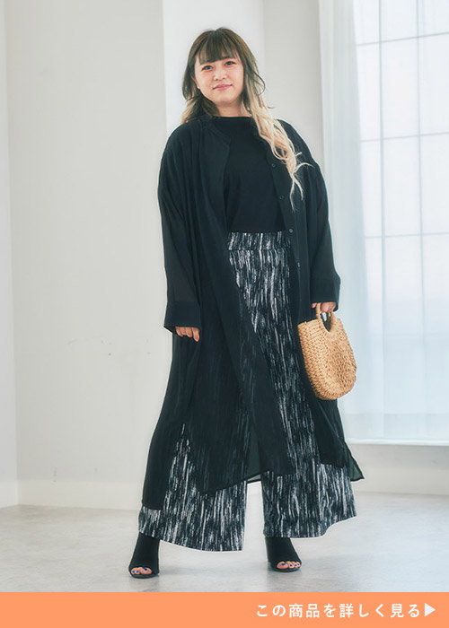 黒のトップス×白黒の柄パンツに黒のシアーロングカーディガンを羽織る女性