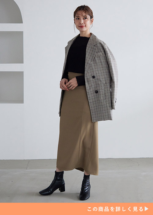 黒トップス×カーキのナロースカートに、チェック柄のジャケットを肩掛けする女性