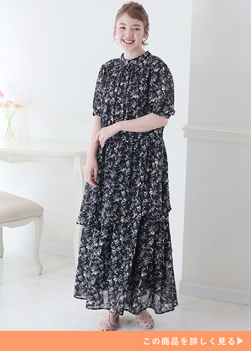 黒ベースの小花柄ティアードデザインワンピースを着る女性