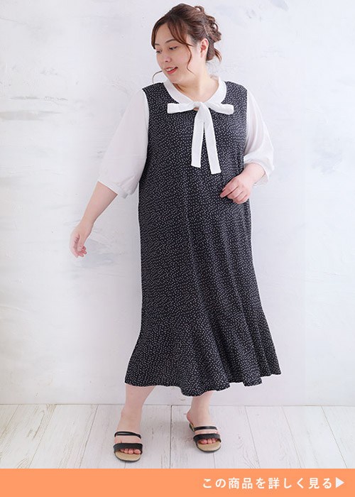 ドット柄のリボンタイ付きワンピースに合わせて黒いサンダルを履く女性