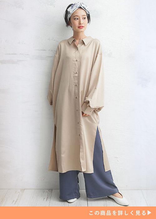 ベージュのランタンスリーブワンピースとグレーのコーデに白いパンプスを履く女性