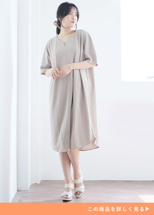 ベージュのハートネックワンピースに合わせてアイボリーのサンダルを履く女性