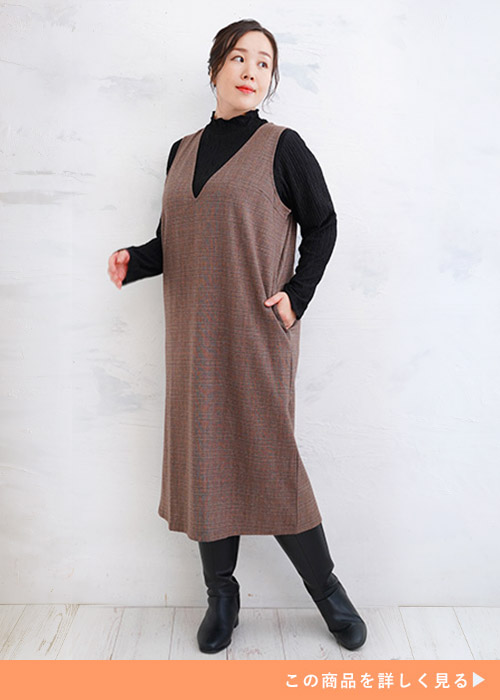 ブラウンチェックのジャンスカにブラックハイネックニットとブーツを合わせる女性