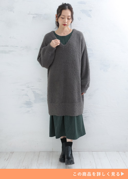 グレーのニットワンピにストライプ柄のワンピをレイヤードする女性