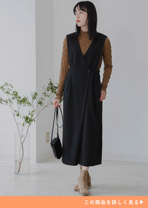 ブラックのジャンスカとブラウンのハイネックニットのコーデにベージュのブーツを履く女性