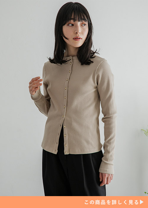 ベージュのトップスを着て、黒のボトムを履く女性。