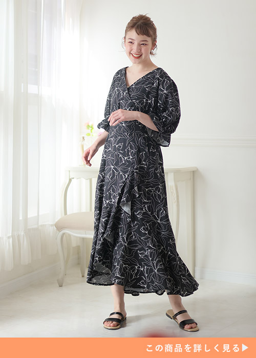 黒地に線画で花柄を描いたカシュクールデザインのワンピースを着る女性