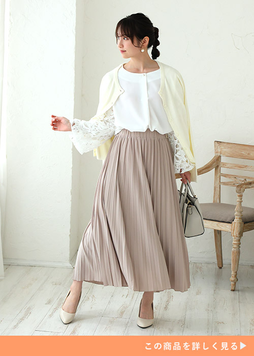 袖レースの白トップス×ベージュのプリーツスカートを着て、白のカーディガンを肩掛けする女性
