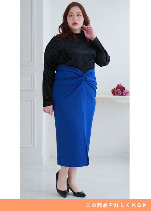 黒のベロアトップスを着て、青のミモレ丈タイトスカートを履く女性