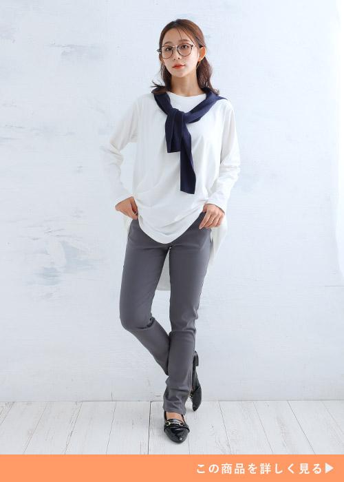 グレーのスキニーパンツにホワイトのロングTシャツを着る女性