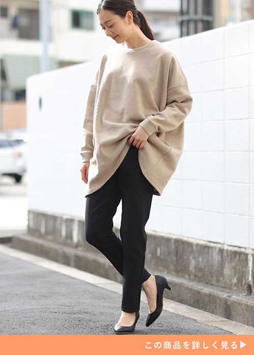 黒のスキニーパンツとベージュのトップスコーデに黒パンプスを履く女性