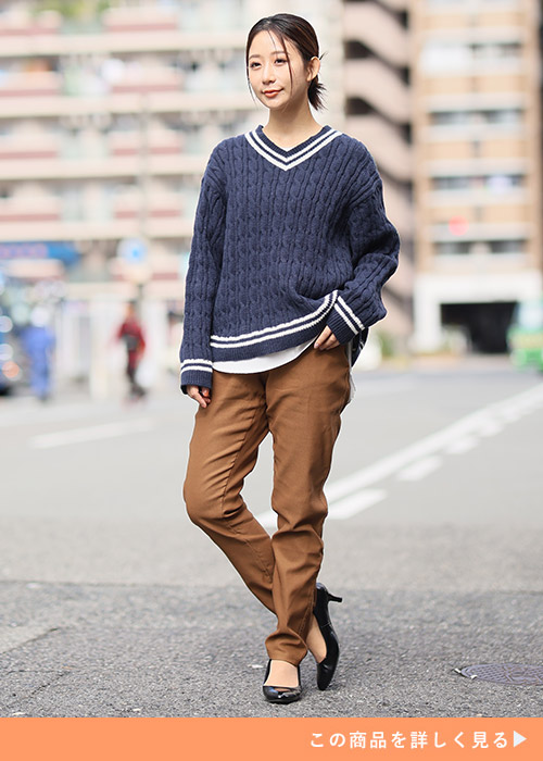 ブラウンのスキニーパンツと白トップス×ブルーニットのレイヤードコーデを着る女性