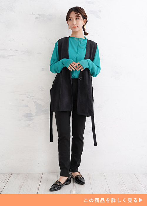 黒スキニーパンツとシアーシャツのコーデに黒ベストとパンプスを合わせる女性