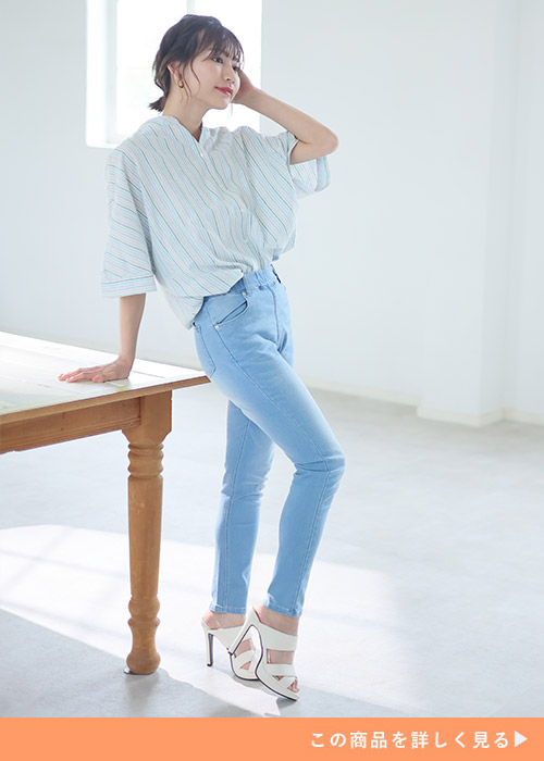 ブリーチ加工のスキニーパンツとストライプシャツのコーデに白サンダルを履く女性