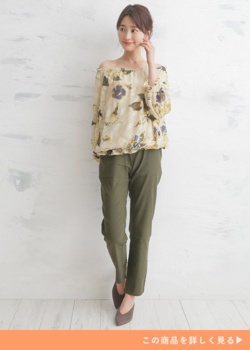 カーキのスキニーパンツとオフショルトップスのコーデにグレーのパンプスを履く女性