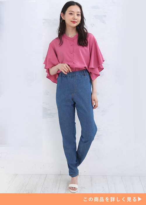 ウエストゴムのデニムスキニーとフリルブラウスのコーデに白いサンダルを履く女性