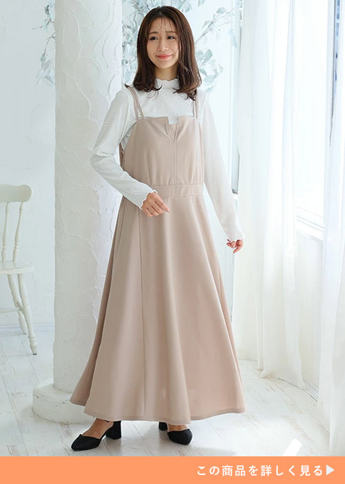 白の長袖ブラウスに、ベージュのキャミワンピを重ね着する女性