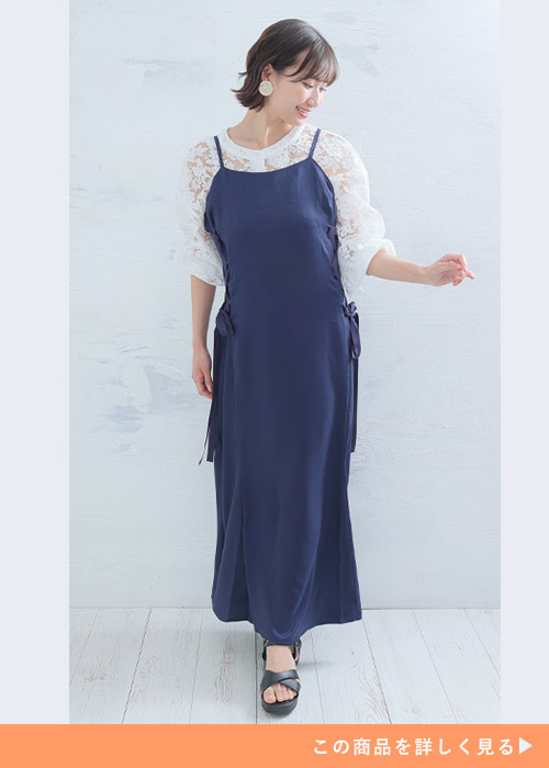 白のレーストップスにネイビーのサイド編み上げキャミワンピを重ね着する女性