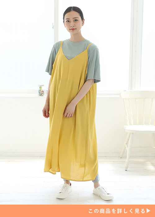 くすみグリーンのTシャツにイエローのキャミワンピを重ね着する女性