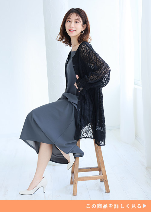 くすみブルーのキャミワンピを着て、黒のロング丈レースカーディガンを羽織る女性