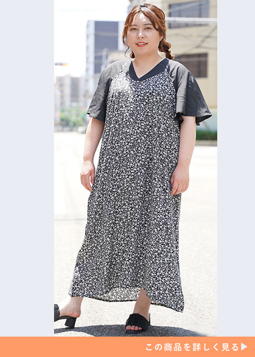 黒のフレア袖トップスに、黒の小花柄キャミワンピを重ね着する女性
