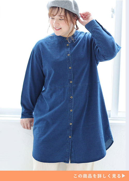 デニム生地のシャツワンピースを着て、白のパンツを履く女性